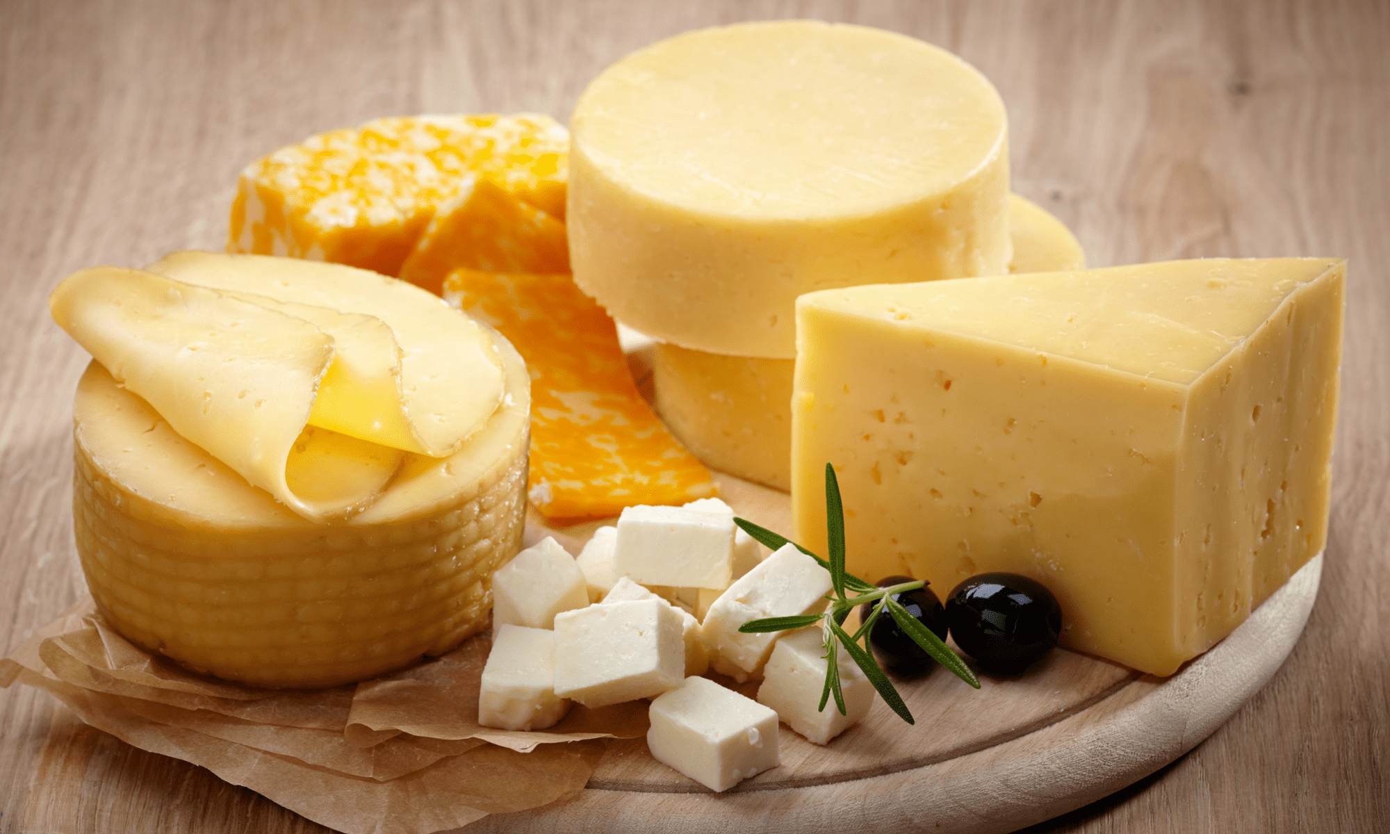 Picture of four types of cheese on wooden round board
